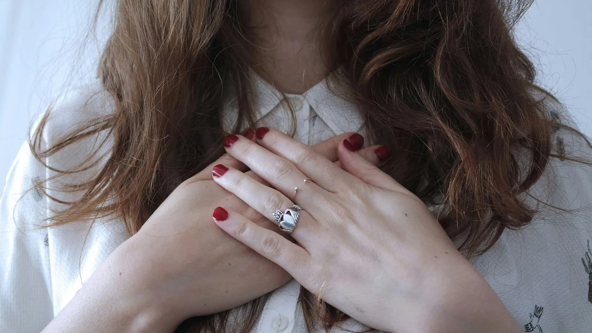 Woman with hands over her heart, Mother's Day grief for motherless mothers