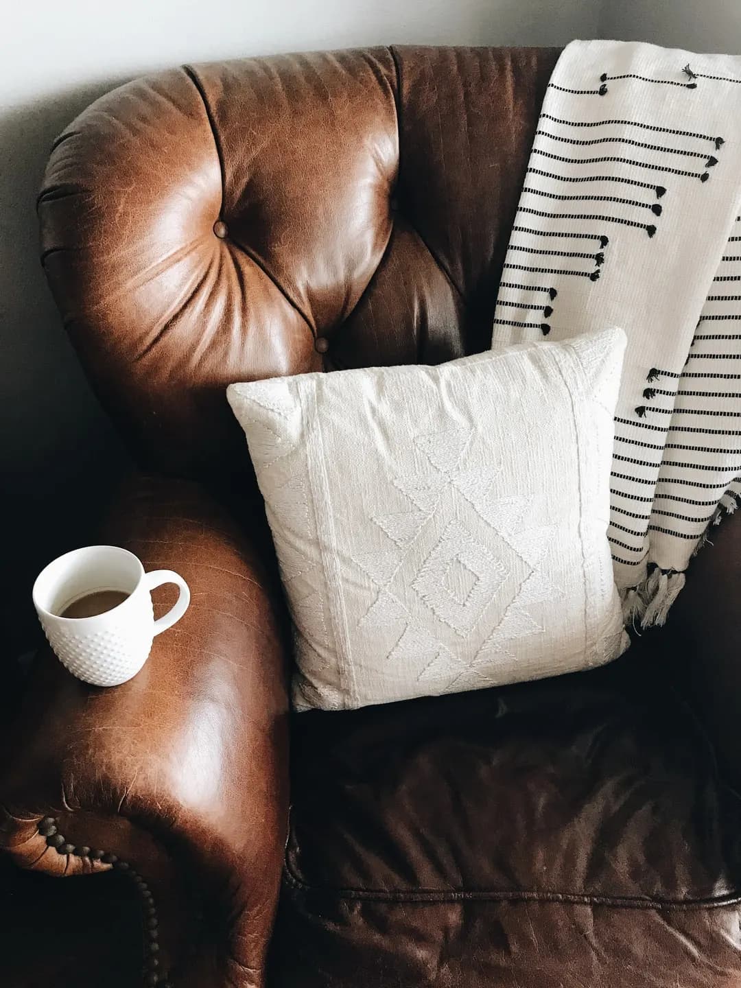 Leather chair with pillow and coffee cup, in-person versus virtual therapy in North Carolina
