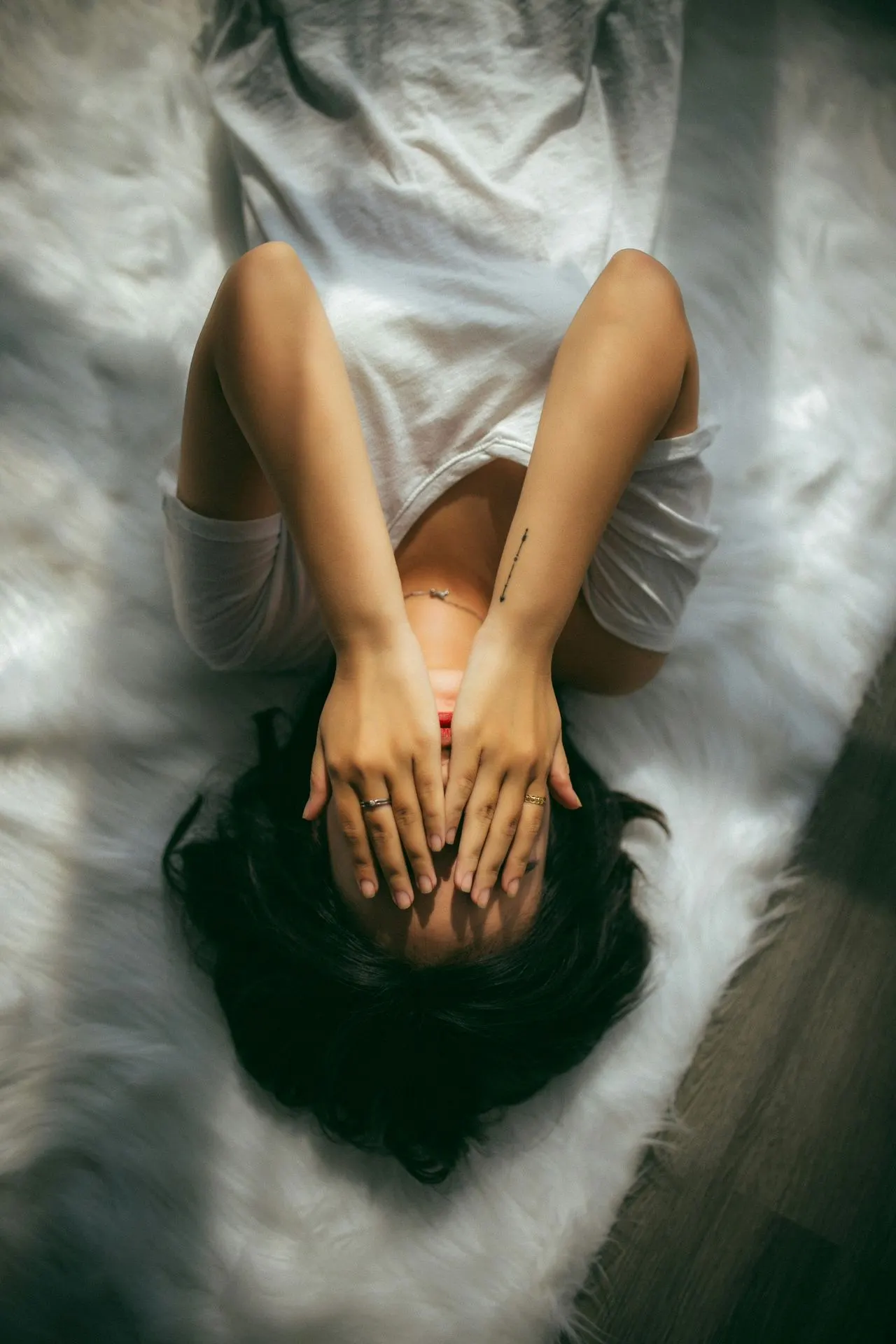 Woman lying down with hands over her face, overthinking and anxiety therapy in Charlotte, NC